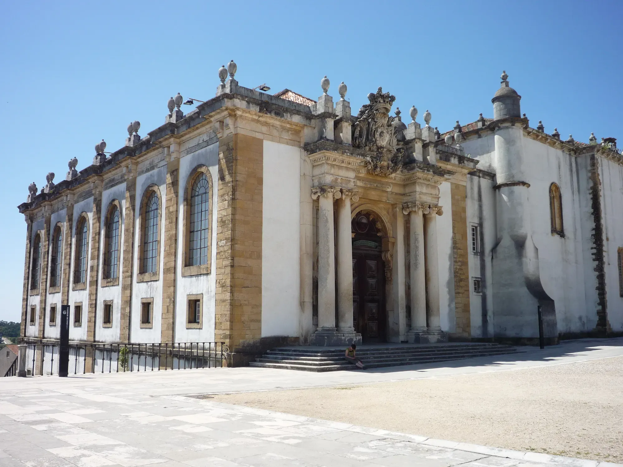 The white baroque stone portal and façade of the Biblioteca Joanina at the University of Coimbra