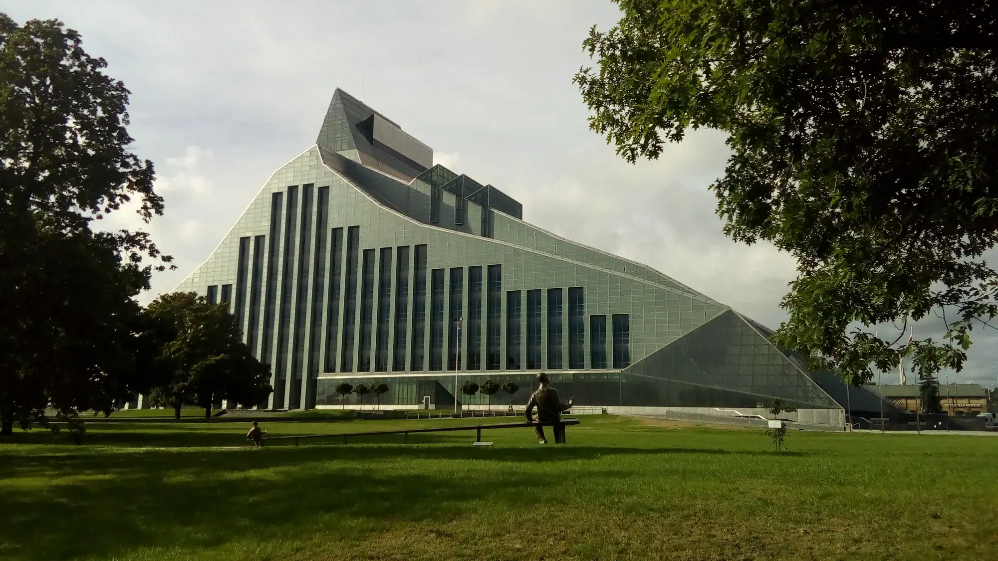 The National Library of Latvia, a glass building with a dark stepped roof rising like a hill, a lawn in front