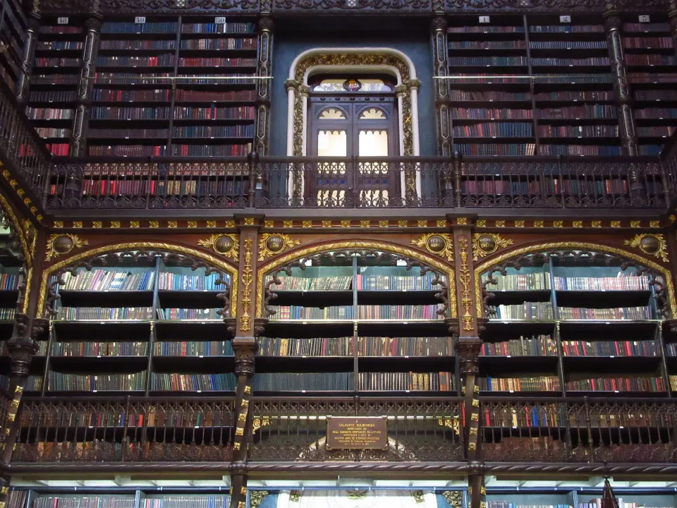 The reading room of the Royal Portuguese Cabinet of Reading, dark carved wooden galleries of books under Gothic-revival arches
