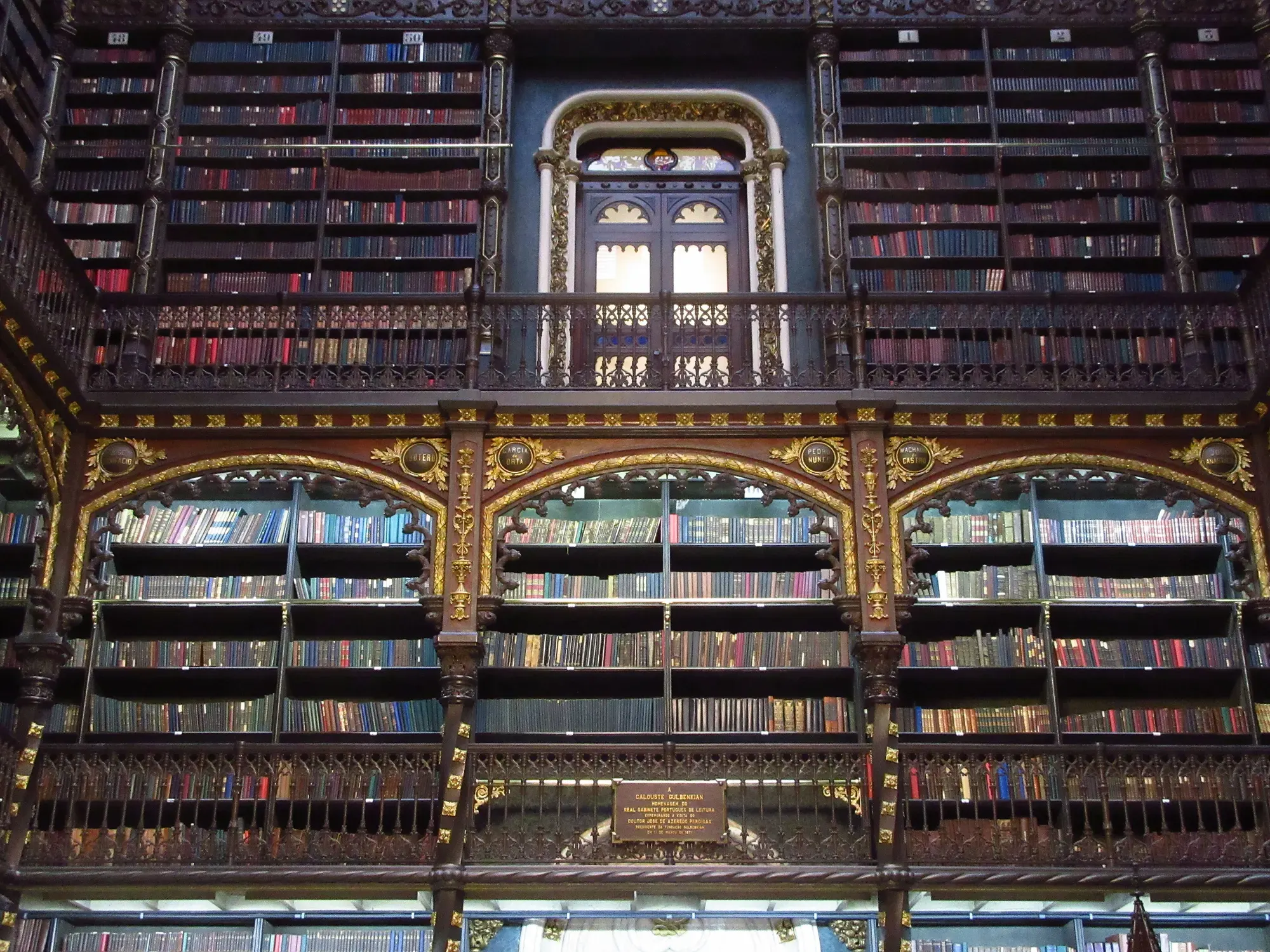 The reading room of the Royal Portuguese Cabinet of Reading, dark carved wooden galleries of books under Gothic-revival arches